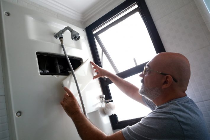 Zamaitis mostra medidor do consumo de água dentro do banheiro de seu apartamento. FOTO: HELVIO ROMERO/ESTADÃO